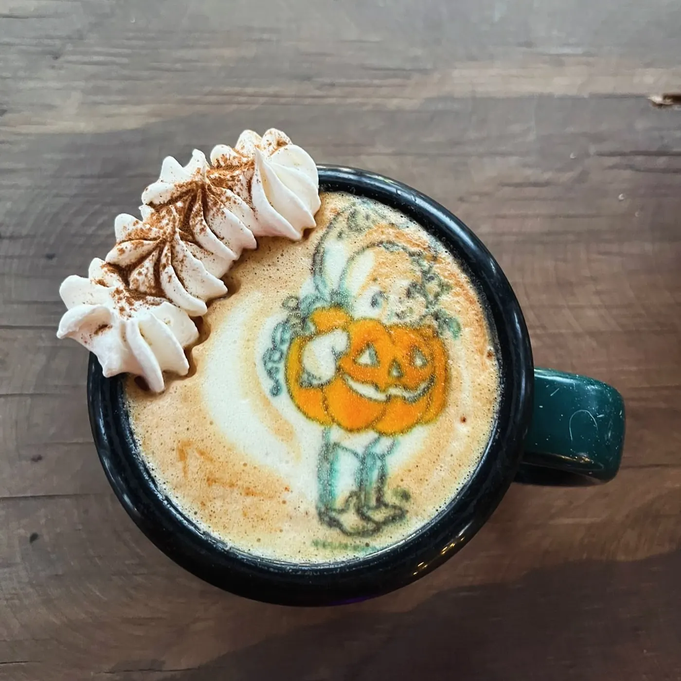 Taza de peltre con un muñeco calabaza impreso en la espuma y crema batida