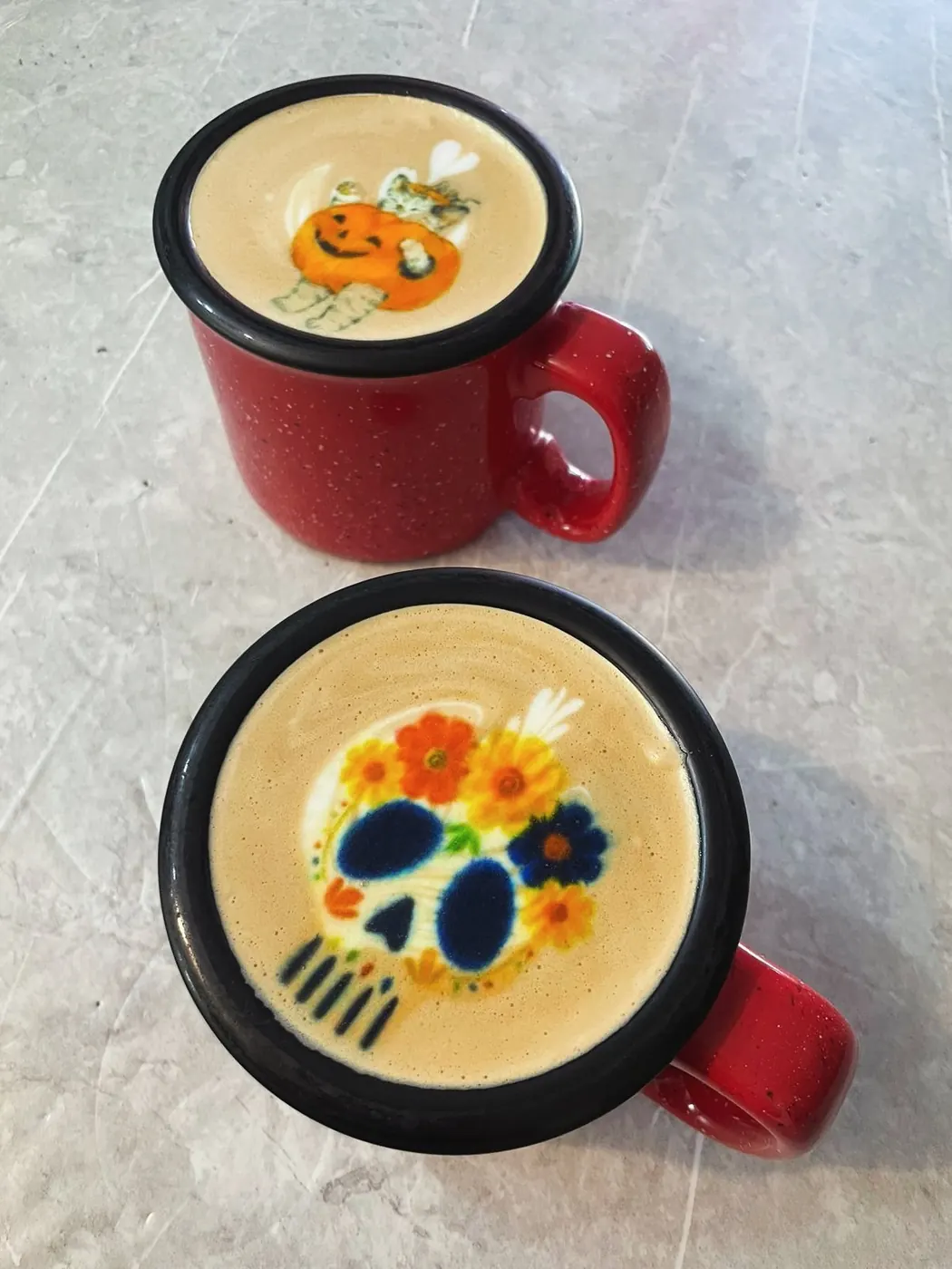 Dos tazas de peltre rojas con calaveras de colores impresas en la espuma